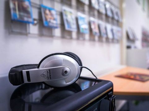 Kopfhoerer, Tisch und Blue-rays an Wandregal